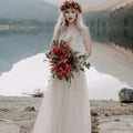 Bride wearing the Champagne Lace and Tulle Wedding dress 1205, holding a red  wild flower bouquet beside a mountain lake.