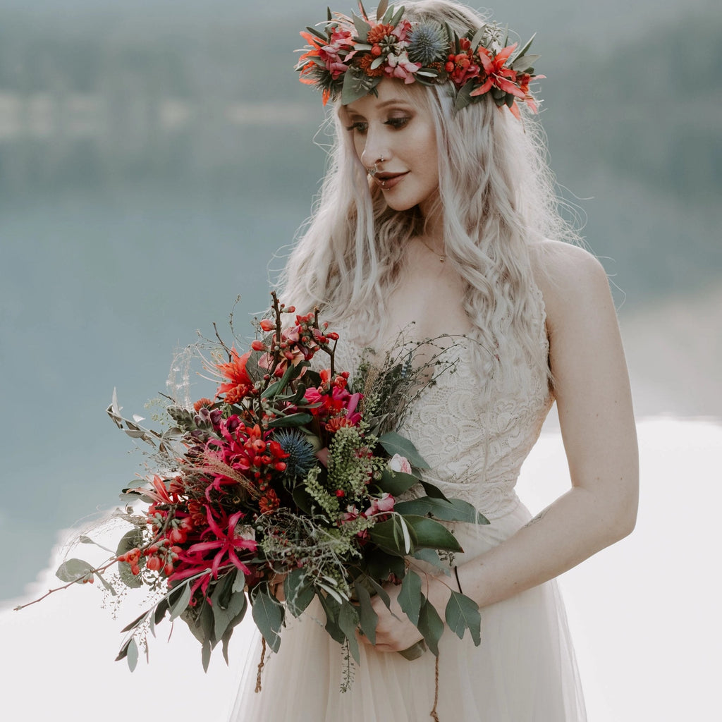 Bride wearing the Champagne Lace and  Tulle Wedding Dress holding a red wildflower bouquet beside a mountain lake.