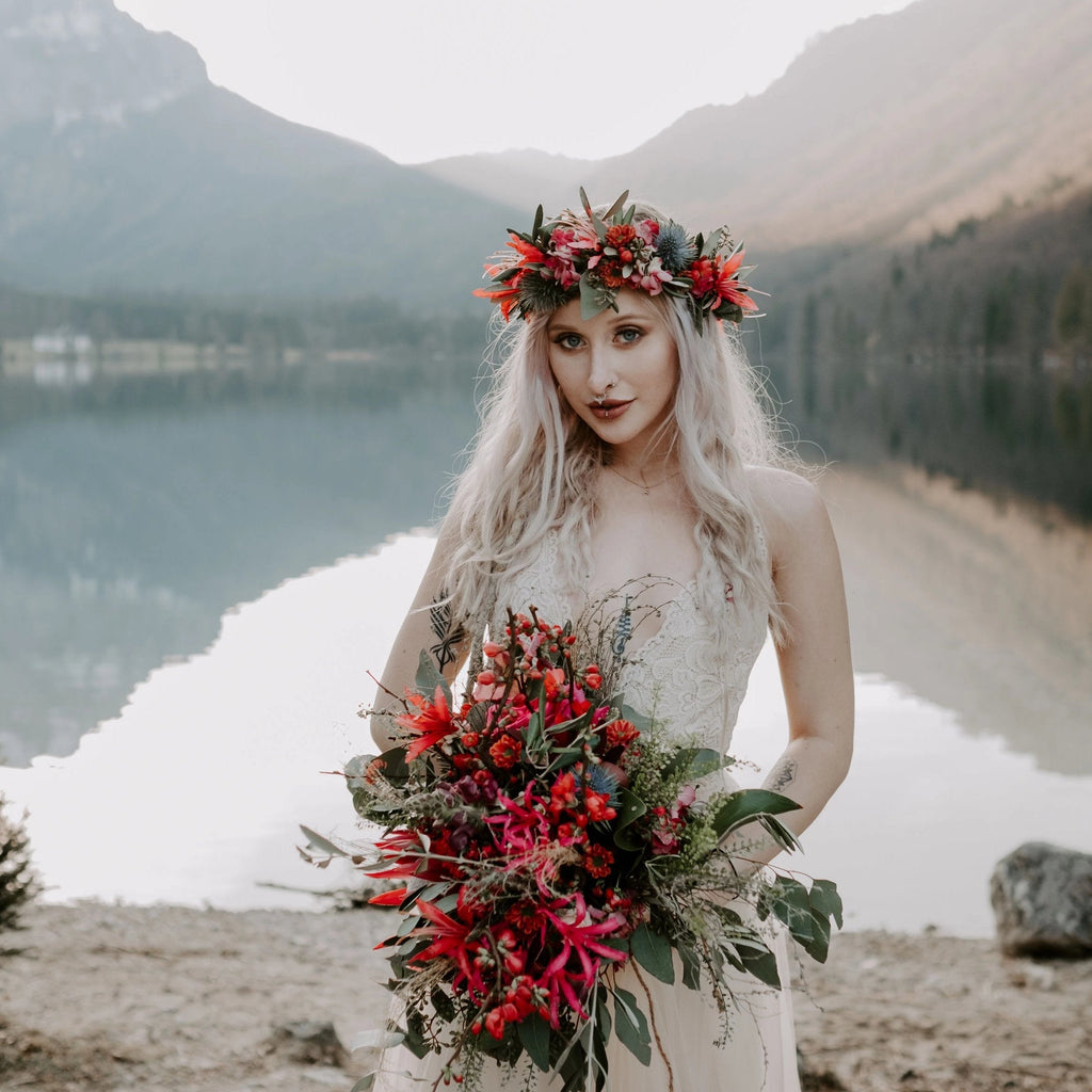 Bridal wearing the Champagne Lace and Tulle Wedding, holding a red wildflower bouquet beside a mountain.