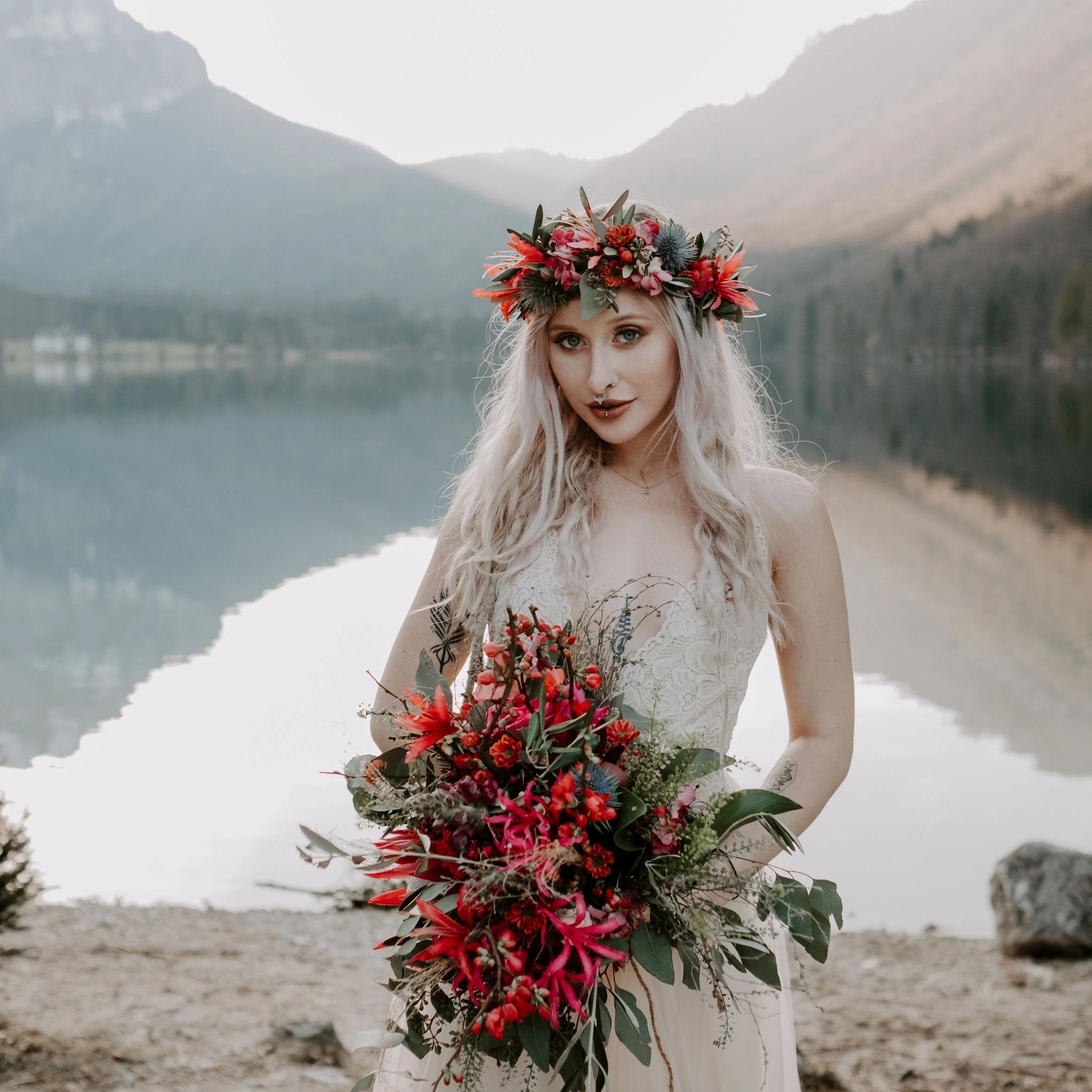 Bridal wearing the Champagne Lace and Tulle Wedding, holding a red wildflower bouquet beside a mountain.