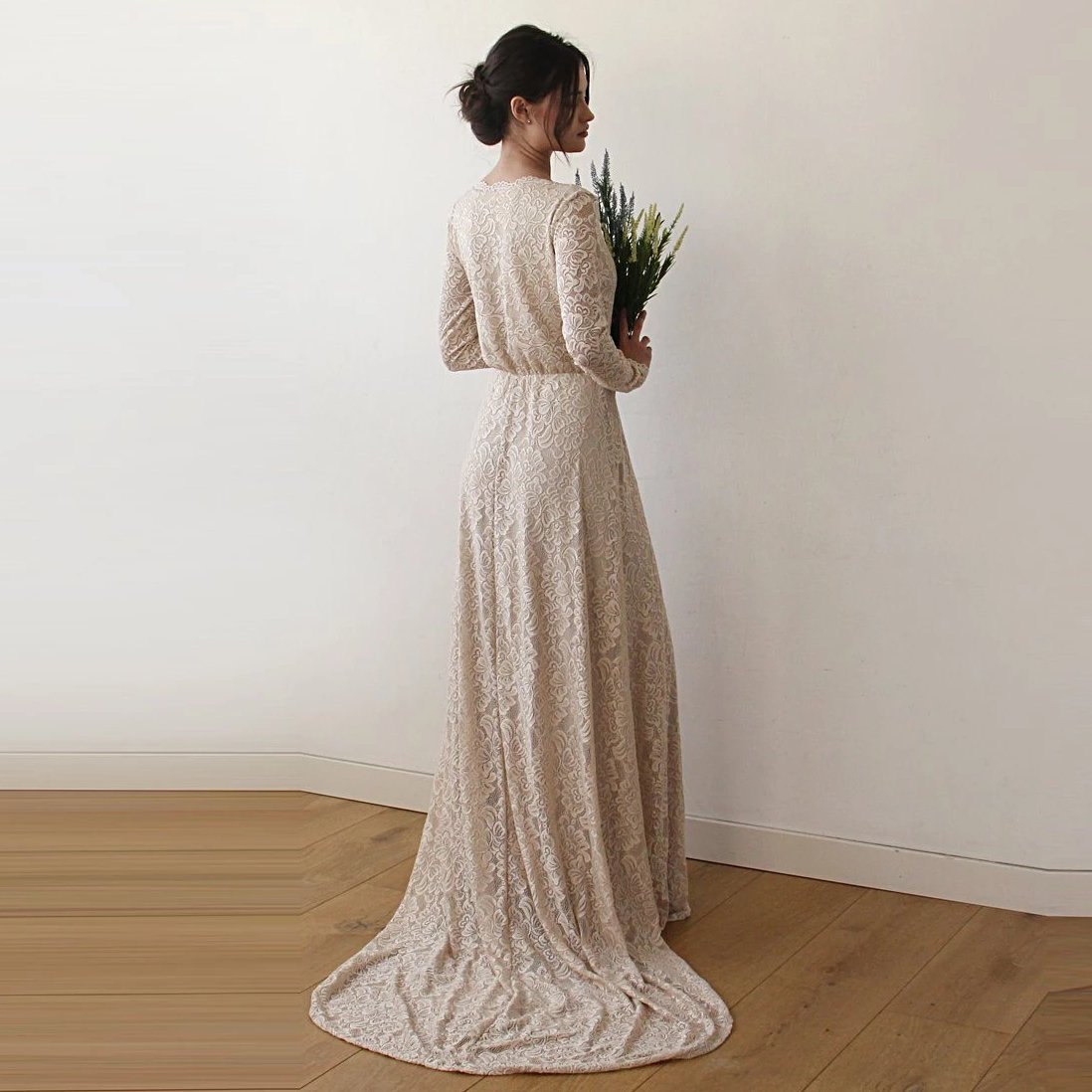 Rear-view of bride wearing a champagne wrap lace wedding gown showing flowing train and long lace sleeves.