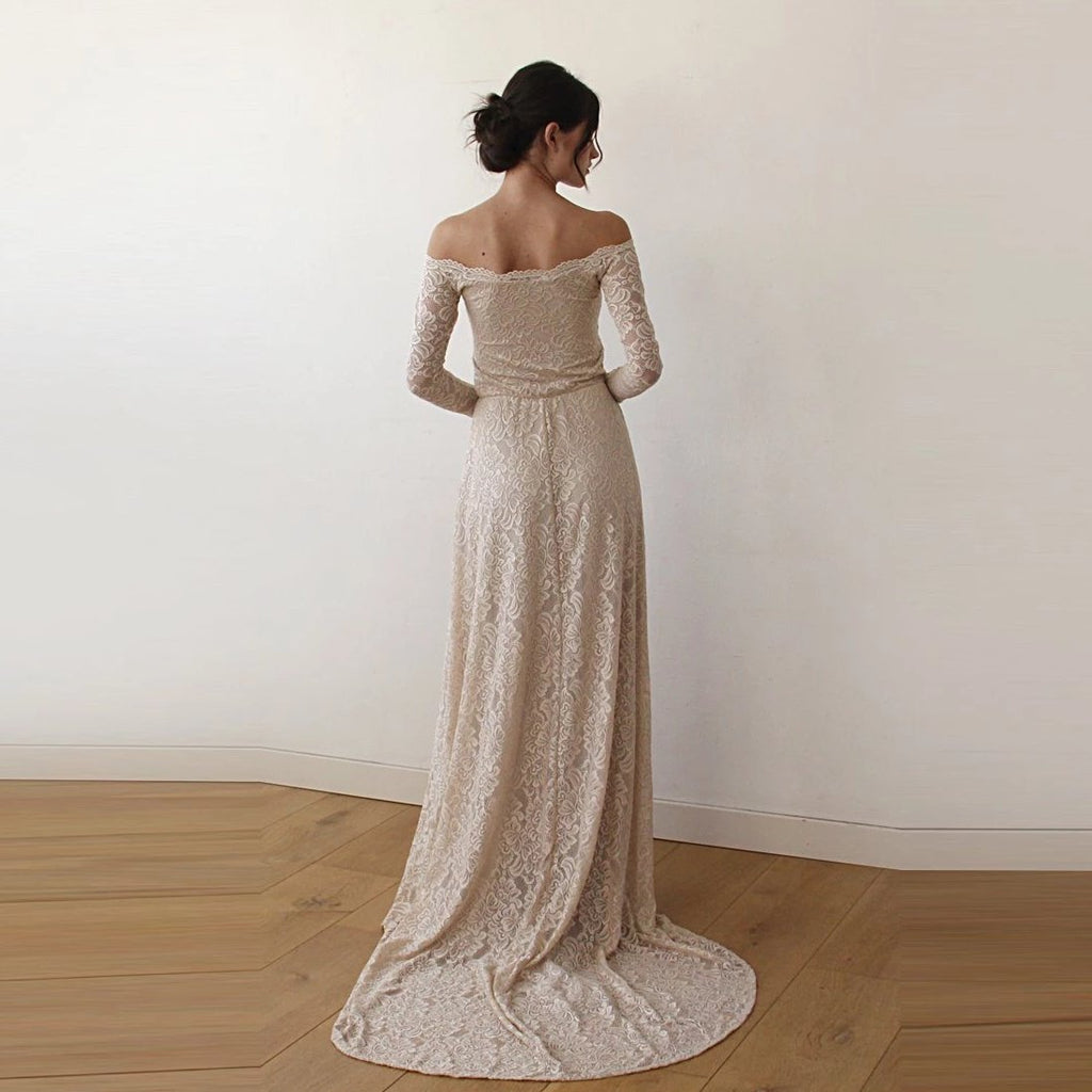 Back view of model wearing a champagne off-shoulder lace wedding gown with long sleeves, fitted silhouette, and extended train.