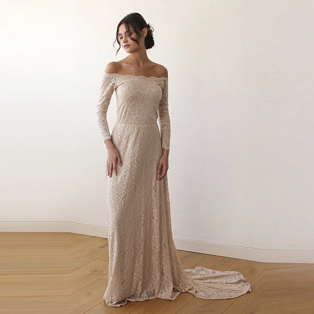 Front view of model wearing a champagne off-shoulder lace wedding gown with long sleeves, fitted silhouette, and trailing train.