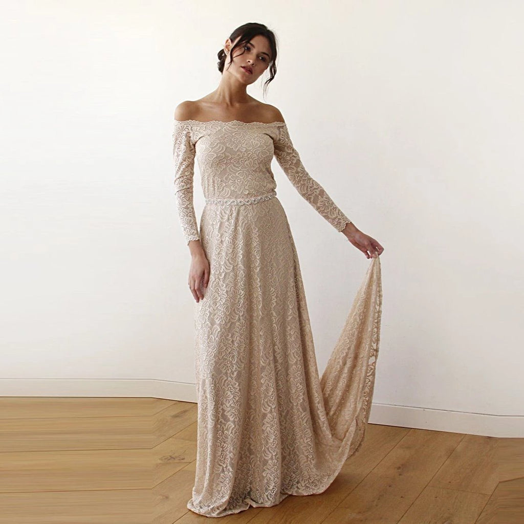 Front view of model wearing a champagne off-shoulder lace wedding gown with long sleeves, fitted silhouette, and softly lifted train.
