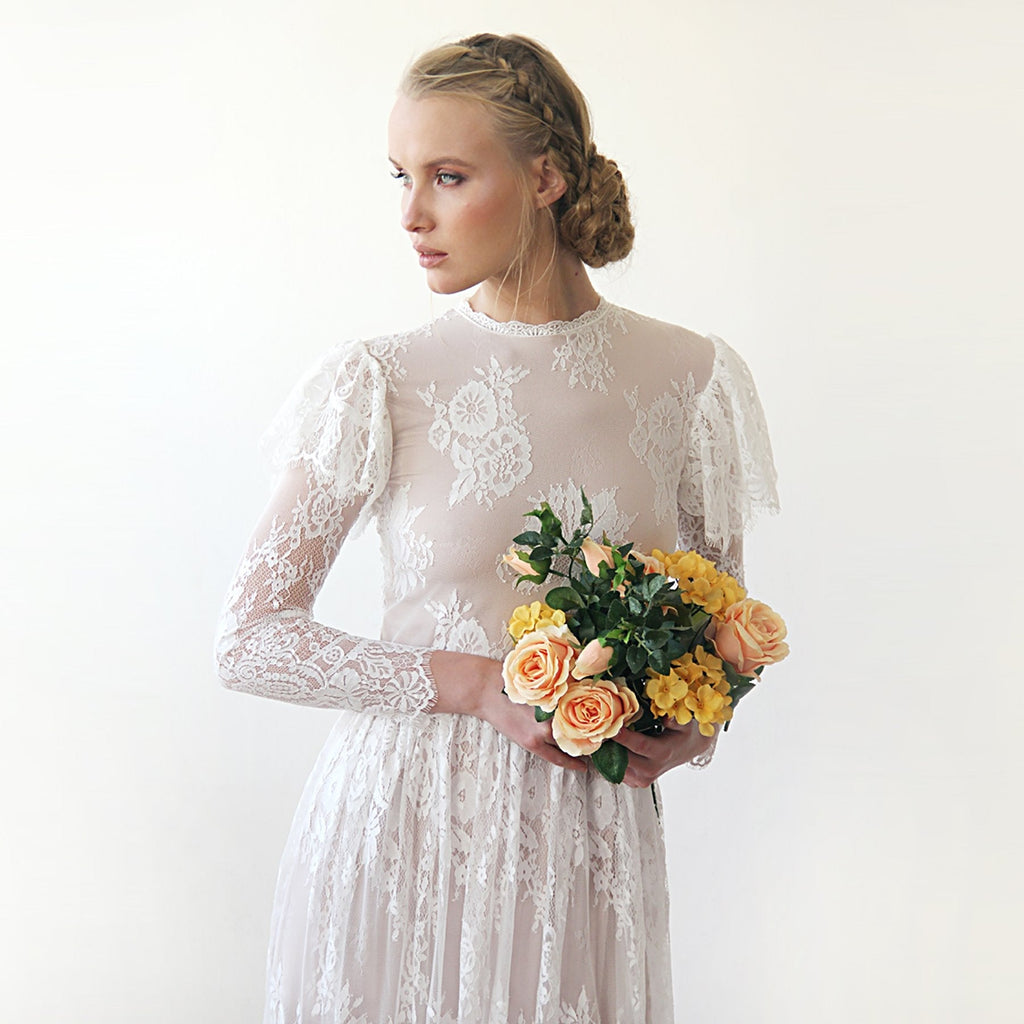 Front view of model with a rose  bouquet wearing a woodland vintage lace wedding gown with high neckline, sheer long lace sleeves, flutter sleeve overlay, and soft bridal bouquet.