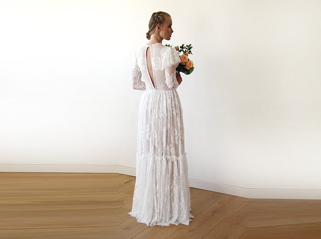 Full-length back view of model wearing an ivory woodland vintage lace wedding gown with open keyhole back, flutter sleeve overlay, sheer long lace sleeves, tiered skirt, and bridal bouquet.